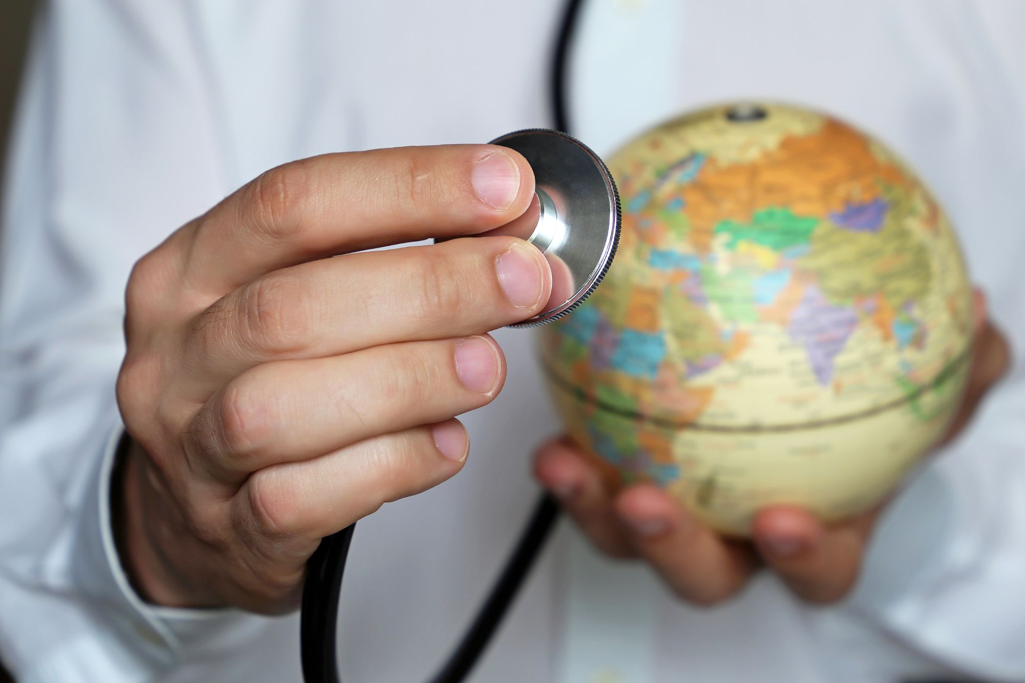 Globe in the background with hand holding stethoscope in the foreground